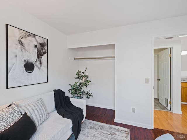 living area with baseboards, visible vents, and wood finished floors