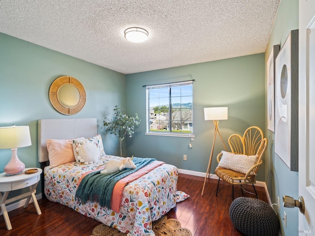 bedroom with baseboards, a textured ceiling, and hardwood / wood-style floors