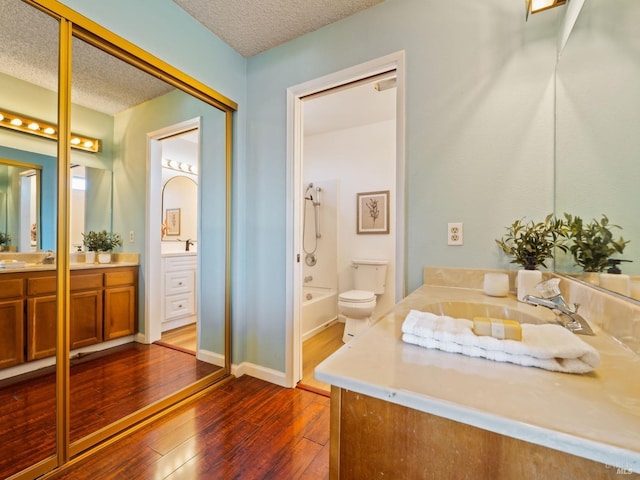 full bath with hardwood / wood-style flooring, baseboards, a textured ceiling, and vanity