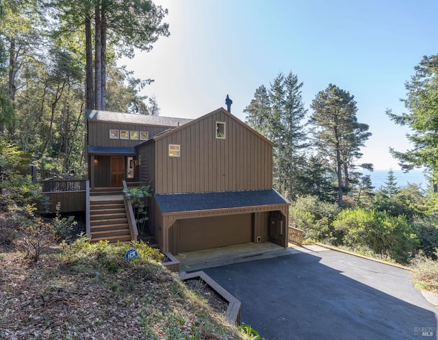 rustic home with stairs, aphalt driveway, roof with shingles, and a garage