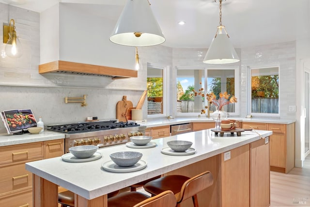 kitchen with decorative backsplash, light countertops, light brown cabinetry, wall chimney range hood, and stainless steel dishwasher