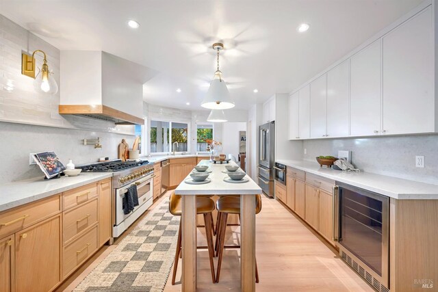 kitchen with backsplash, a sink, wall chimney range hood, high quality appliances, and beverage cooler