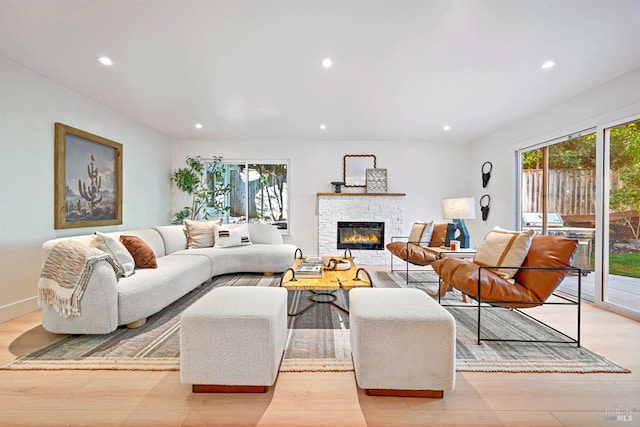 living room with light wood-style floors, recessed lighting, and a stone fireplace