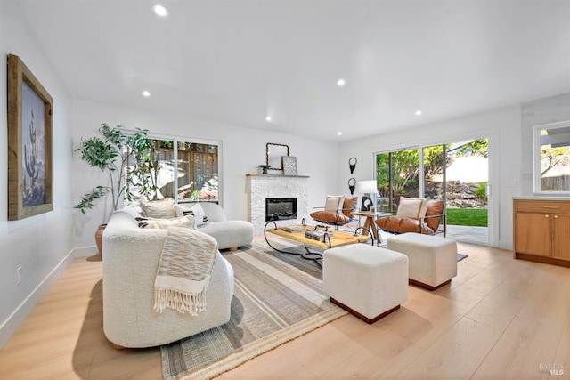 living room with recessed lighting, baseboards, a fireplace, and light wood finished floors