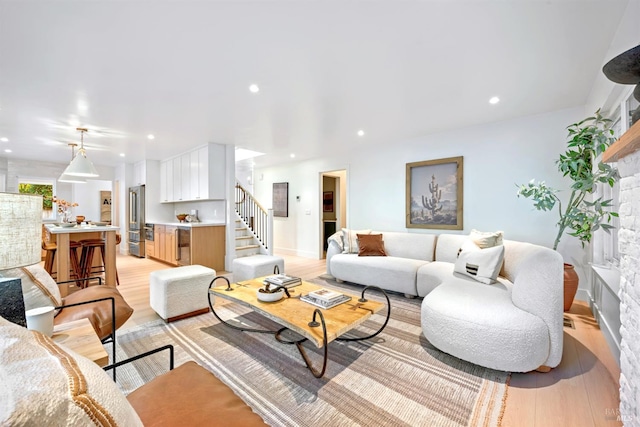 living room with light wood-style floors, recessed lighting, and stairs