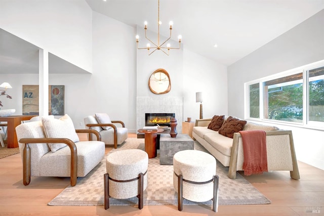 living room featuring a tiled fireplace, high vaulted ceiling, and light wood-type flooring