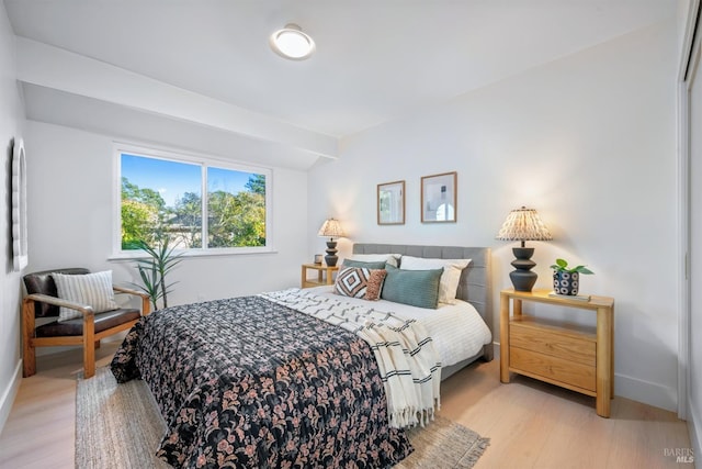 bedroom with light wood-style flooring, baseboards, and vaulted ceiling