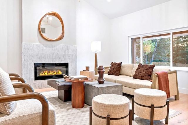 living area featuring light wood-type flooring and a glass covered fireplace