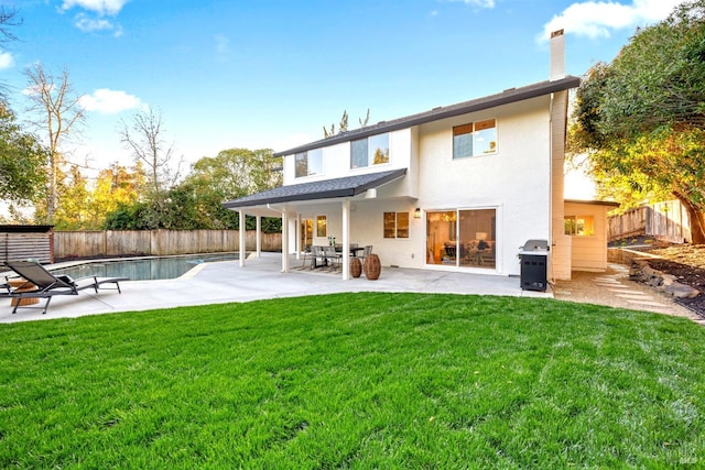 rear view of property featuring a fenced backyard, a lawn, stucco siding, a chimney, and a patio area