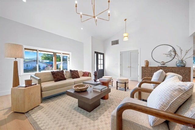 living area with baseboards, visible vents, an inviting chandelier, light wood-type flooring, and high vaulted ceiling