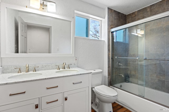 bathroom with a textured wall, a sink, and double vanity