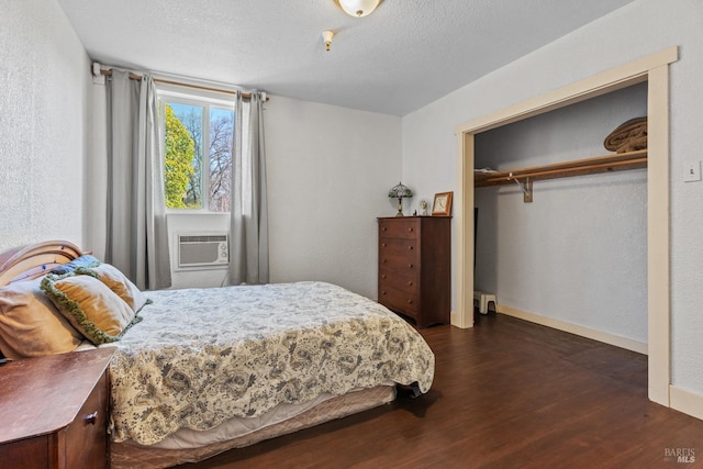 bedroom featuring a textured ceiling, cooling unit, baseboards, a closet, and dark wood finished floors