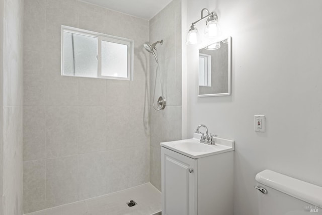 full bathroom with toilet, a tile shower, and vanity