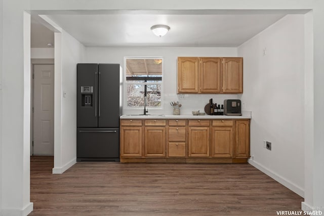 kitchen with dark wood-style flooring, a sink, baseboards, light countertops, and fridge with ice dispenser