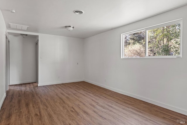 spare room featuring visible vents, baseboards, and wood finished floors