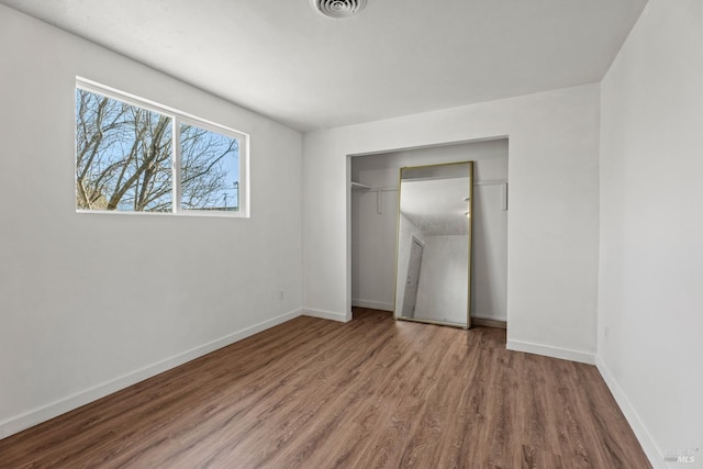 unfurnished bedroom with baseboards, a closet, visible vents, and wood finished floors