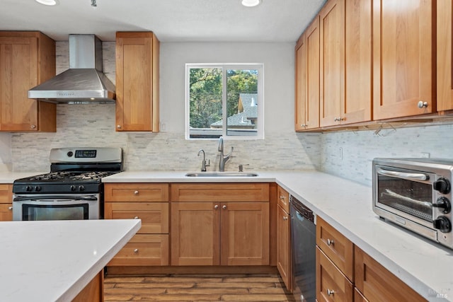 kitchen featuring backsplash, a sink, wall chimney range hood, stainless steel gas range oven, and dishwashing machine