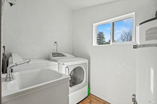 laundry room with laundry area, wood finished floors, a sink, baseboards, and independent washer and dryer