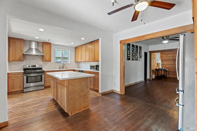 kitchen featuring stainless steel appliances, backsplash, wall chimney range hood, and wood finished floors