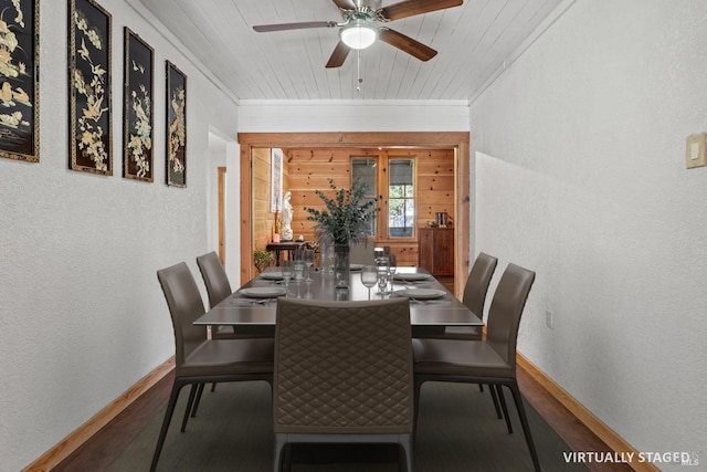 dining area with wooden walls, baseboards, wood finished floors, and a textured wall