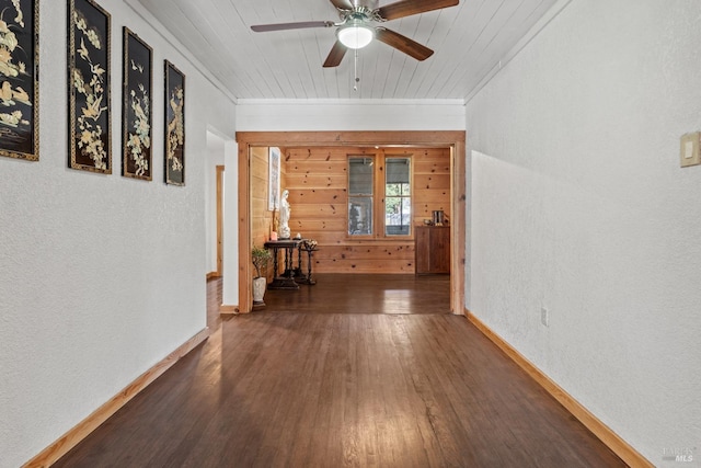 hallway with a textured wall, ornamental molding, wood ceiling, wooden walls, and wood finished floors