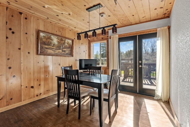 dining room with wooden ceiling, wood walls, wood finished floors, baseboards, and french doors