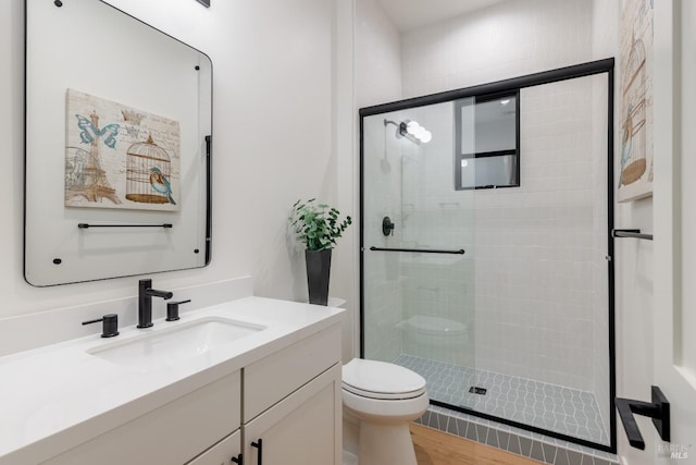 full bathroom with a shower stall, toilet, vanity, and wood finished floors