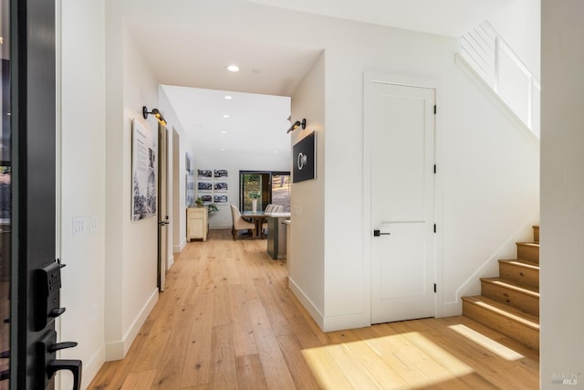 hall featuring recessed lighting, light wood-type flooring, stairs, and baseboards