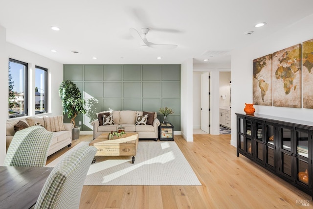 living area with an accent wall, light wood-style flooring, recessed lighting, and a ceiling fan