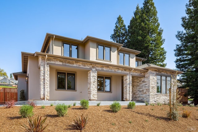 prairie-style house with stucco siding, stone siding, and fence