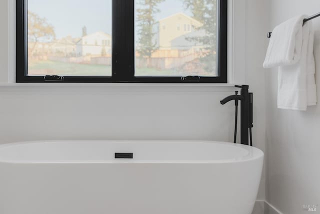 bathroom featuring a wealth of natural light and a soaking tub