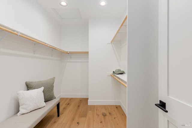 spacious closet with light wood finished floors and attic access