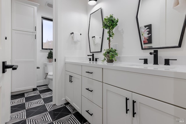 bathroom with tile patterned floors, double vanity, toilet, and a sink