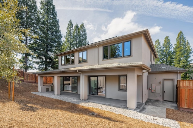 rear view of house with a patio, fence, and stucco siding