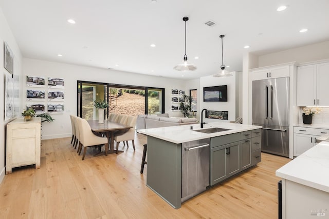 kitchen with light wood-style flooring, gray cabinets, a sink, white cabinetry, and stainless steel appliances