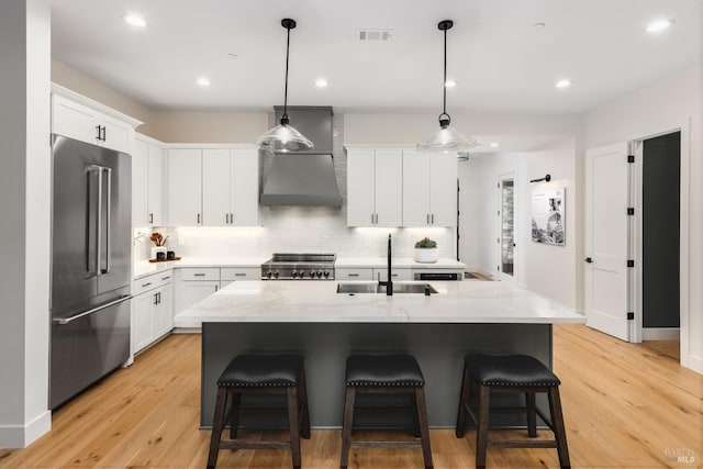 kitchen with visible vents, a kitchen bar, a sink, stove, and high end refrigerator