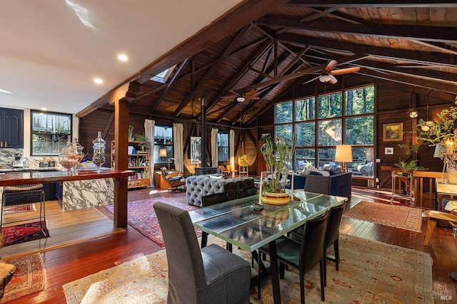 dining room with high vaulted ceiling, hardwood / wood-style floors, wood walls, and a ceiling fan