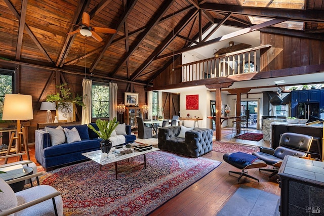 living area with hardwood / wood-style floors, beamed ceiling, wooden ceiling, and wood walls