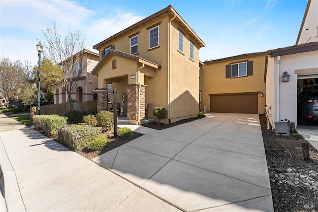 view of front of house featuring a garage, concrete driveway, fence, and stucco siding