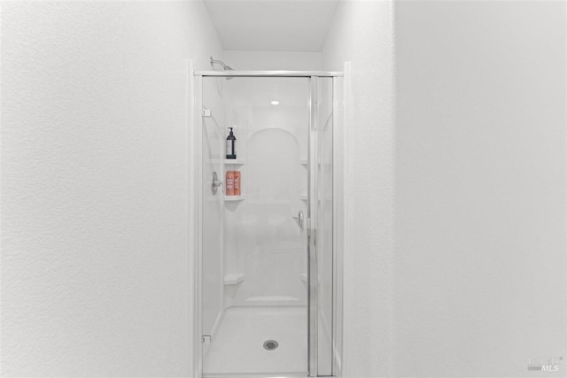 full bath with a textured wall and a stall shower
