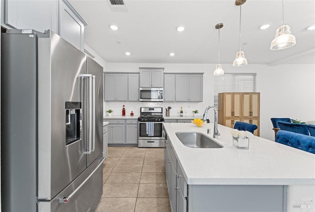 kitchen featuring light tile patterned floors, backsplash, gray cabinetry, appliances with stainless steel finishes, and a sink