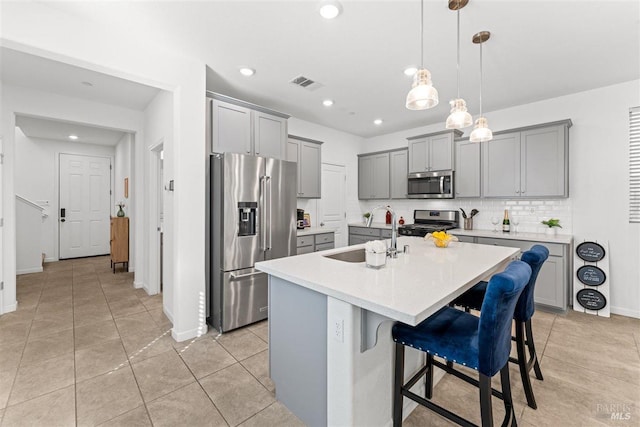 kitchen with stainless steel appliances, gray cabinetry, visible vents, and a sink