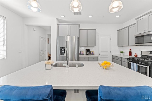 kitchen with stainless steel appliances, a breakfast bar, and gray cabinets