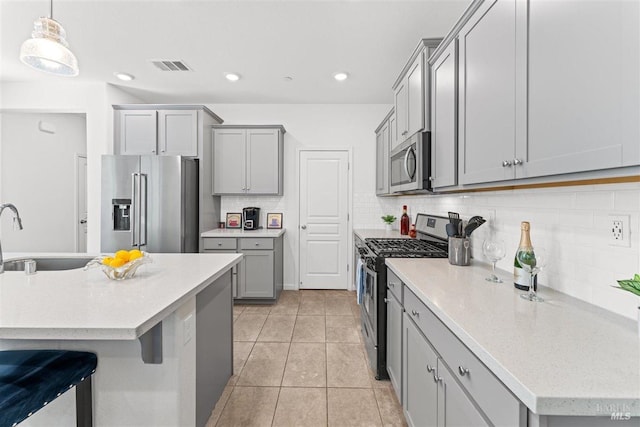 kitchen with appliances with stainless steel finishes, a sink, gray cabinetry, and visible vents