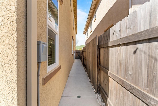 view of side of home with stucco siding and fence