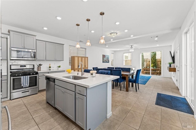 kitchen with a sink, ceiling fan, appliances with stainless steel finishes, and gray cabinetry