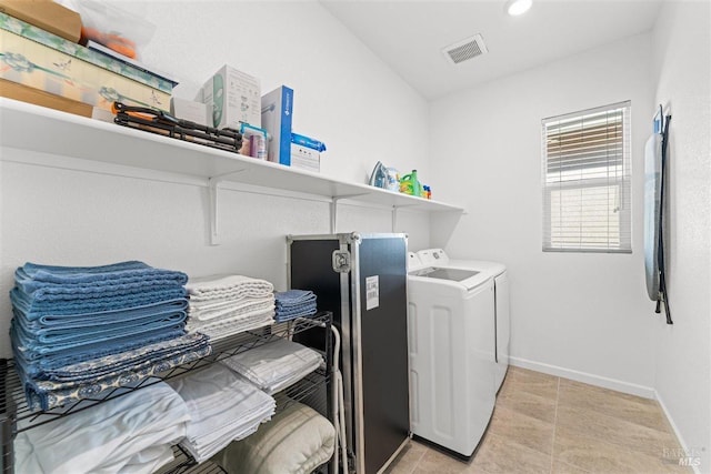 washroom with baseboards, light tile patterned flooring, visible vents, laundry area, and washing machine and clothes dryer