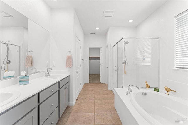 full bath featuring a sink, double vanity, a stall shower, a spacious closet, and a garden tub