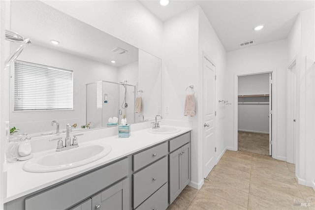 bathroom with a shower stall, double vanity, visible vents, and a sink
