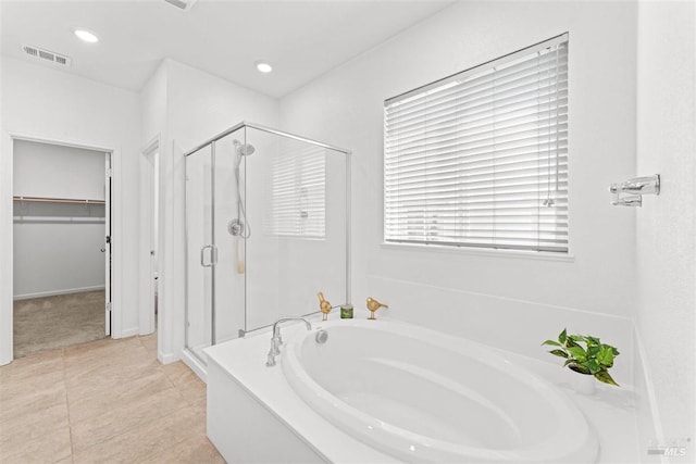 full bath with a spacious closet, visible vents, a garden tub, and a stall shower